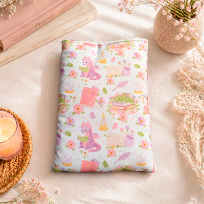 Funda literaria con estampado de dragón lector en tonos rosados y lilas para proteger libros