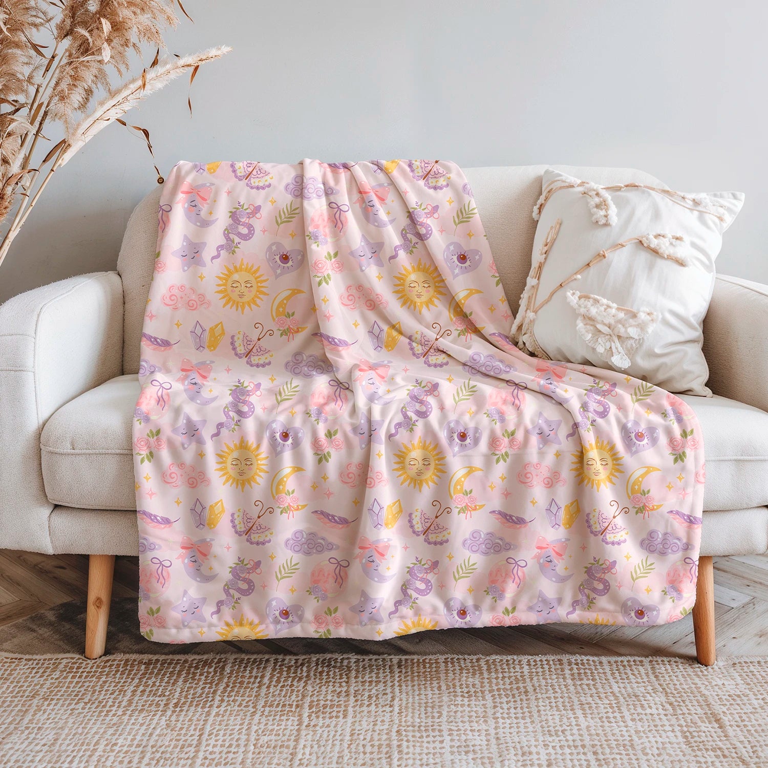 Manta de invierno celestial con diseño de lunas, soles, estrellas y cristales en tonos pastel, confeccionada en felpa con reverso sherpa blanco.