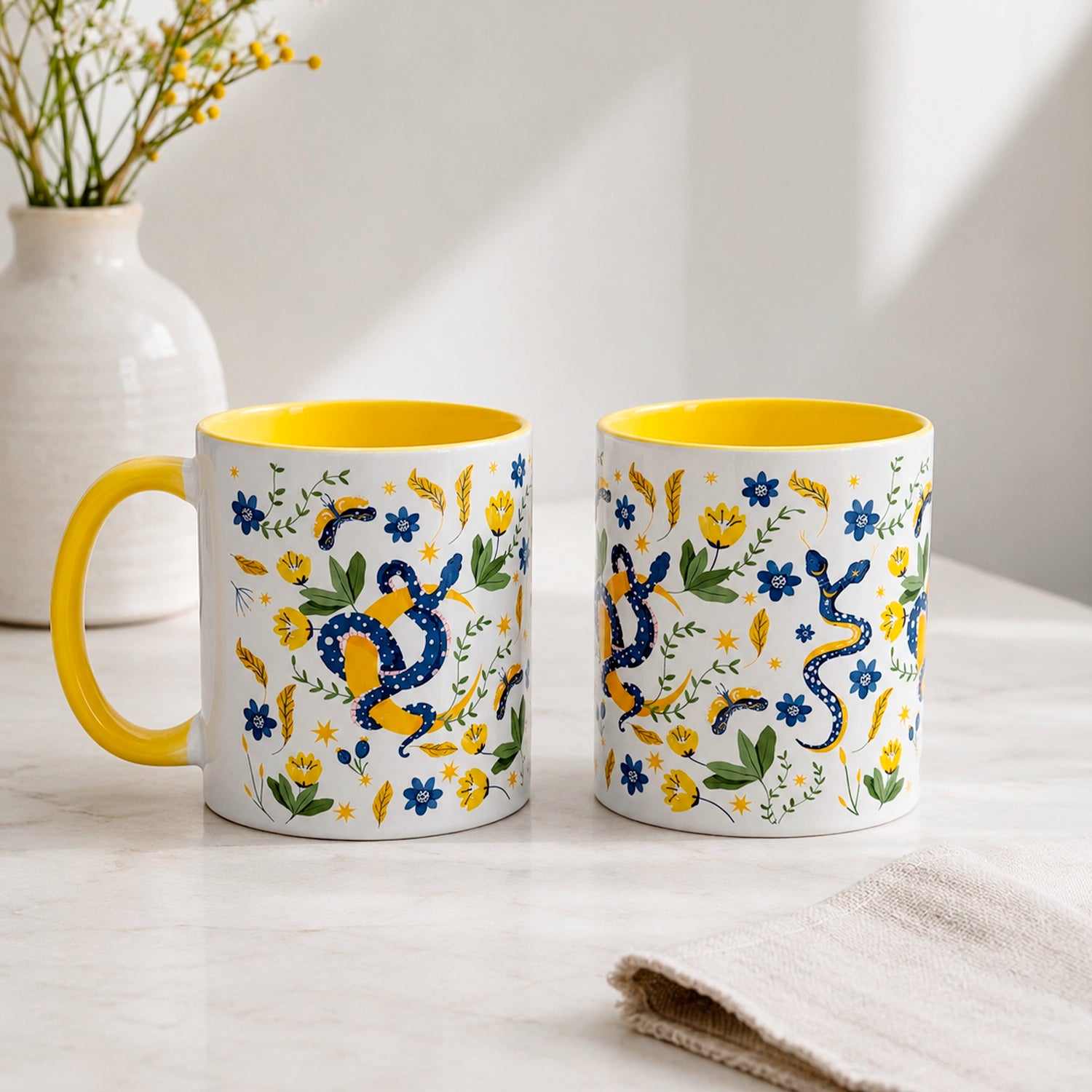 Taza sublimada de 325ml Encanto de Serpiente con asa e interior amarillo, diseño místico de serpientes azules, flores, hojas y detalles dorados.
