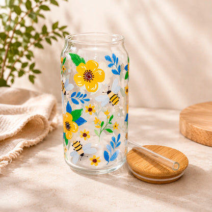 Vaso de vidrio transparente Flores y Abejitas 500 ml con tapa de bambú, bombilla de vidrio y diseño de flores amarillas, hojas azules y abejitas.